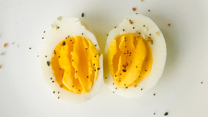 Two egg halves with visible yolk sprinkled with pepper.